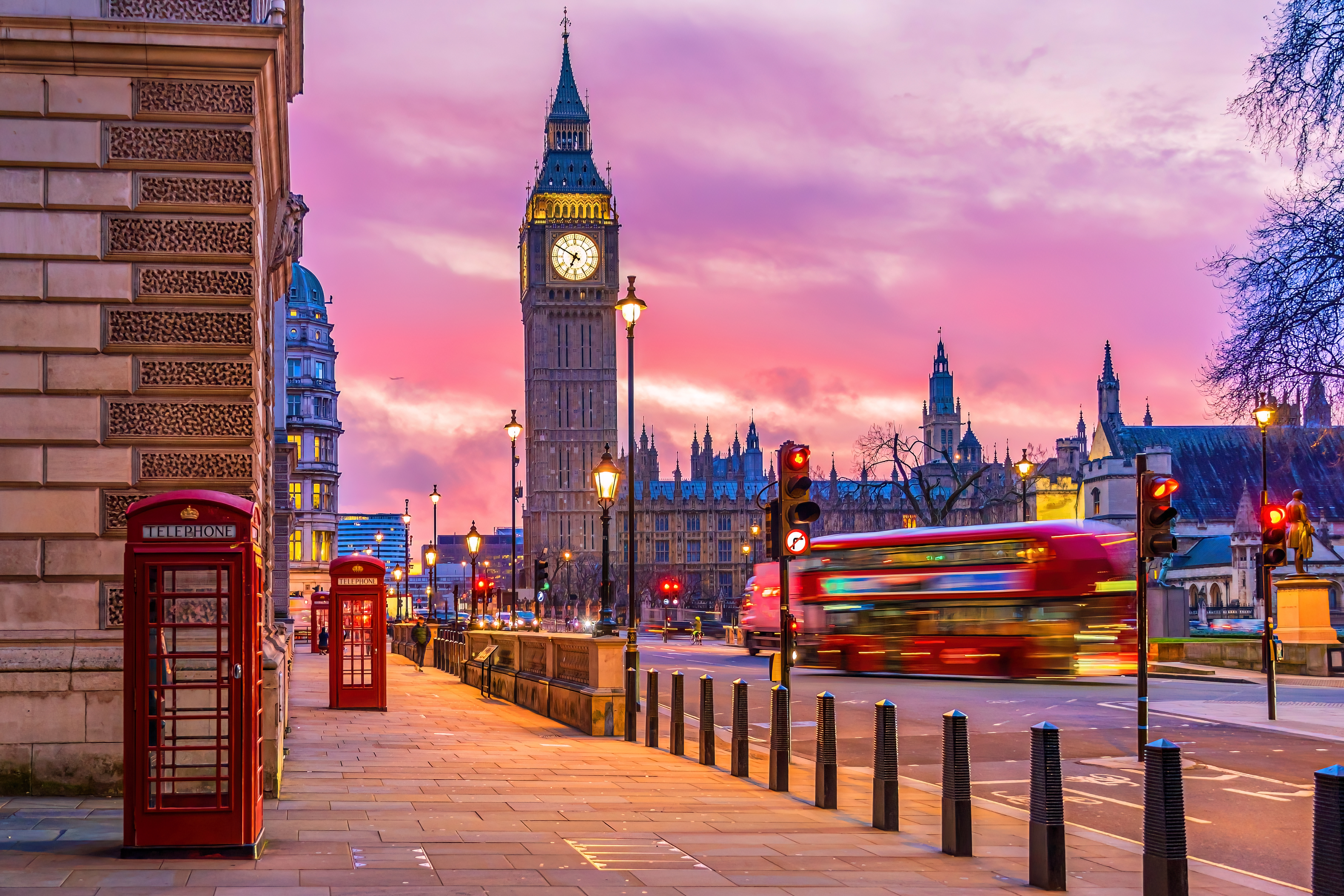London - Big Ben at sunset with red phone boxes and a passing double-decker bus